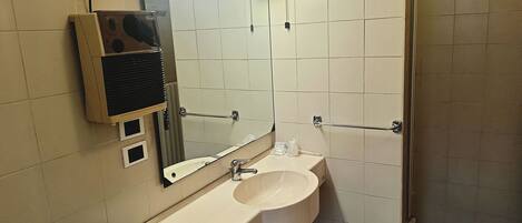 A bathroom with a sink, mirror, towel rack, and a hand dryer.