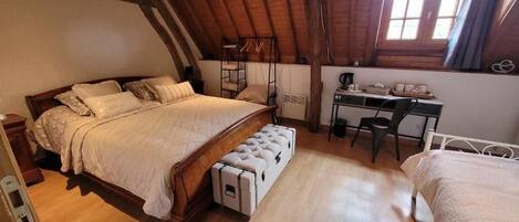 A cozy attic bedroom with a wooden bed, a desk, and a bunk bed.