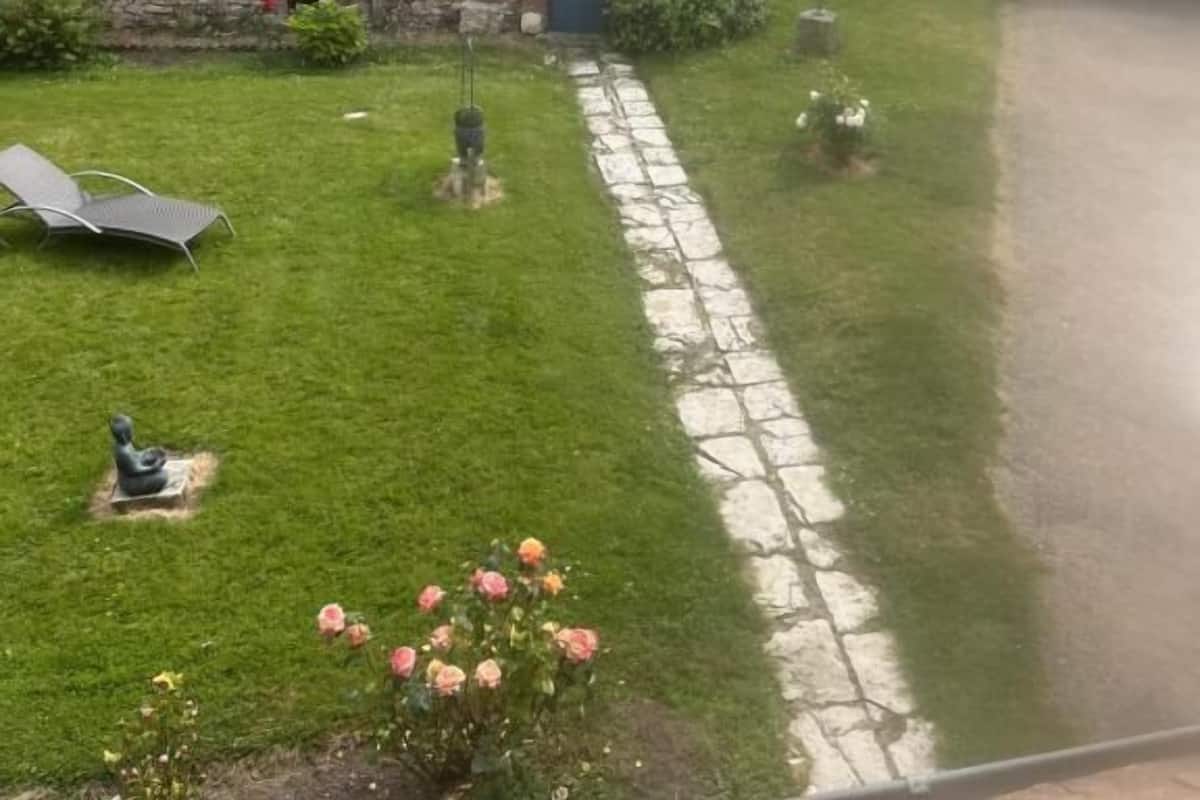 A courtyard with a stone building, a lawn, and a gate.