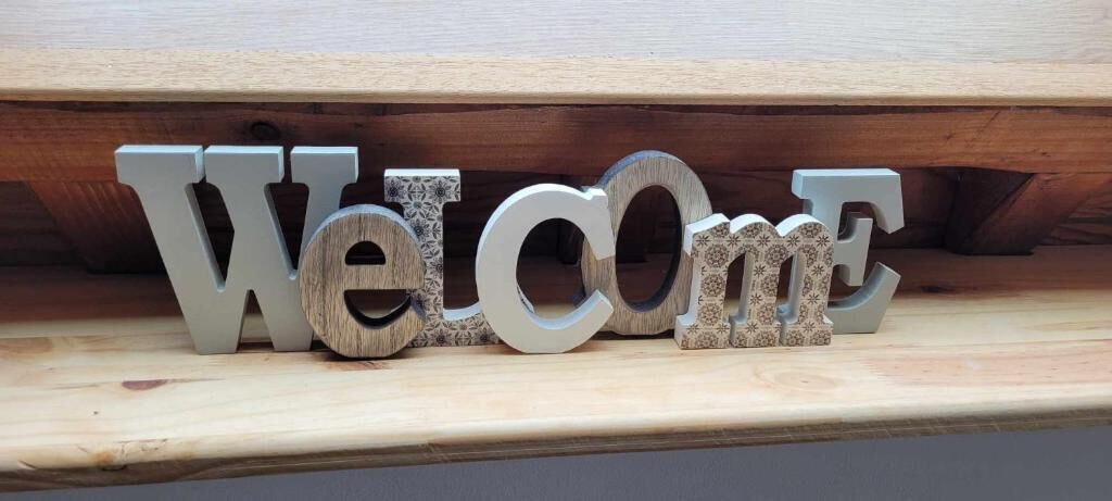 Wooden letters spelling "Welcome" on a shelf.