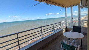 Een overdekt terras met uitzicht op de zee, een tafel en twee stoelen.