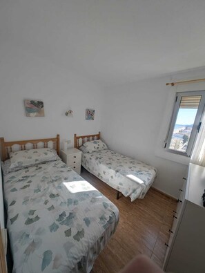 Una camera da letto con due letti, un comodino e una finestra vista.