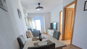 Een eethoek met een tafel voor twee personen, een televisie op de achtergrond en een deur naar een andere kamer.