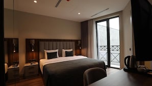 Une chambre d’hôtel moderne dotée d’un grand lit, de tables de chevet, d’un bureau et d’un balcon avec vue.