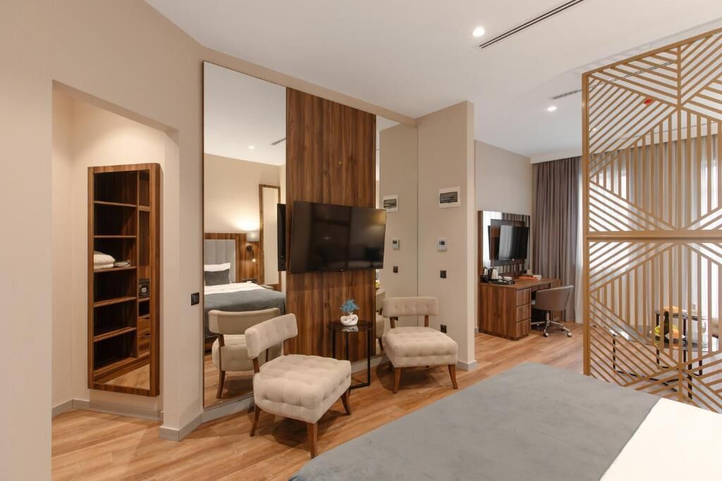 Una camera d'albergo moderna con un armadio in legno, una TV, una scrivania e un angolo salotto.