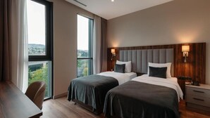 Une chambre d’hôtel avec deux lits, un bureau et une vue sur la ville.