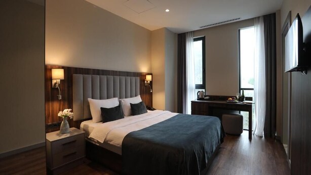 Une chambre d’hôtel moderne, dotée d’un grand lit, de lampes de chevet, d’un bureau et d’une télévision.