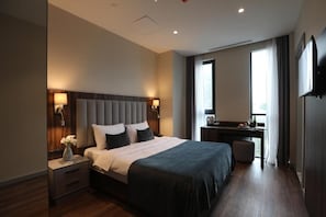 A modern hotel room with a large bed, bedside lamps, a desk, and a television. - White Hill Hotel Tbilisi (Tbilisi)