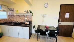 A compact kitchen with a gas stove, a toaster, and a clock on the wall. - 1BR Service Apart Parel 3701 Near TMH By Florastays (Mumbai)