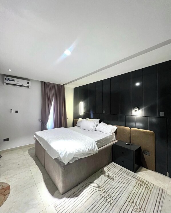 Una camera da letto moderna con un letto grande, un comodino, un armadio e un condizionatore d'aria.