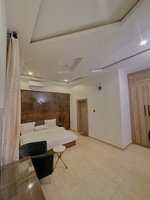 Una camera d'albergo moderna con un letto grande, una scrivania, una sedia e un armadio.