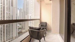 Un balcon avec deux fauteuils en osier, une petite table et une vue sur des immeubles de grande hauteur.
