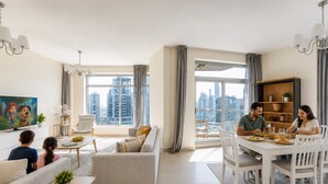 Uma sala de estar moderna com sofá, mesa de jantar, cadeiras, televisão e vista para a cidade.