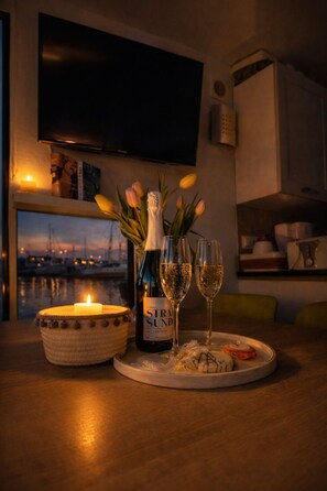 A table with a bottle of wine, two glasses, a candle, and tulips. - ÖKO houseboat Morgenrot with sun terrace & harbor view near Stralsund (Stralsund)