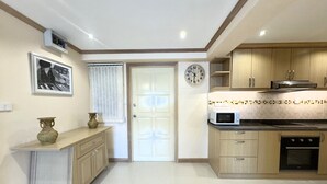 A modern kitchen with wooden cabinets, a microwave, and a clock on the wall. - Stylish 1-bedroom Corner Condo Near Thepprasit Night Market -keha Condominium (Pattaya)