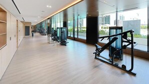 Ein modernes Fitnessstudio mit Trainingsgeräten, großen Fenstern und Holzboden.