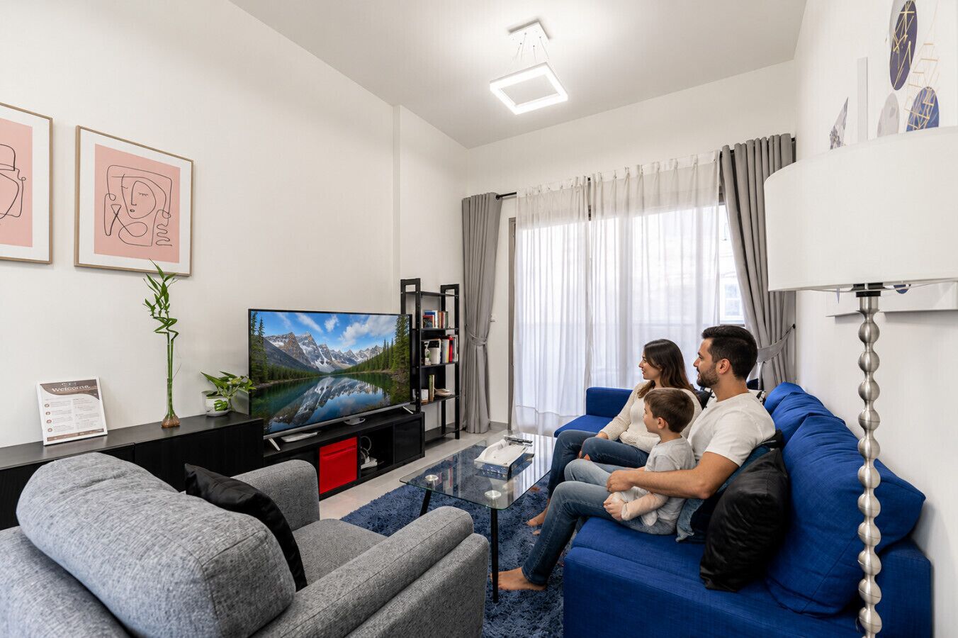 Een woonkamer met een televisie, bank, salontafel en een boekenkast.