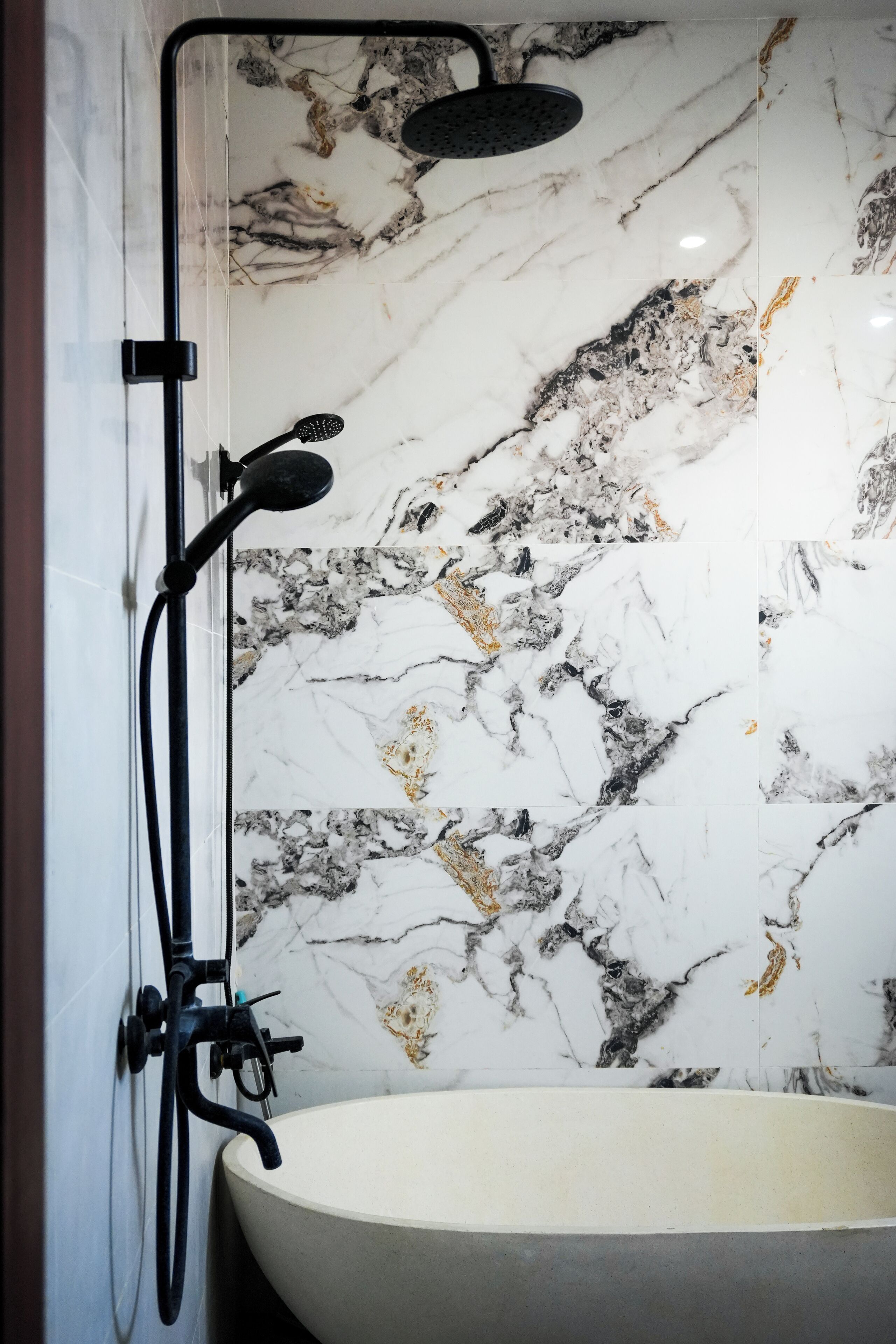 A bathroom with a freestanding bathtub, a showerhead, and a wall-mounted faucet.