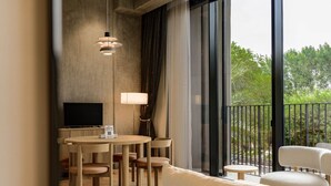 Ein modernes Hotelzimmer mit Balkon, einem runden Esstisch und einem Flachbildfernseher.