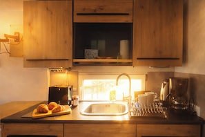 A kitchen with wooden cabinets, a toaster, a coffee maker, and croissants on the counter. - Moonlight houseboat - romance & sunsets near Stralsund (Stralsund)