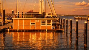 Um barco de madeira atracado em cais, com cabine e vários defensas.