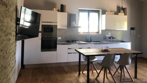 A modern kitchen with white cabinets, a built-in oven, a microwave, and a large window providing natural light.