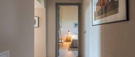 Passadís amb un llit, una làmpada de nit i un quadre al mur.