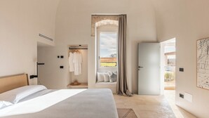 Une chambre à coucher avec un lit, une armoire, une fenêtre avec des rideaux, un banc et une vue sur l’extérieur.
