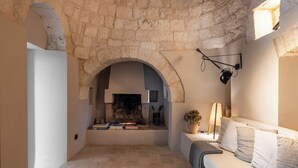 Un intérieur chaleureux avec une arche en pierre, une cheminée, un canapé et une lampe.