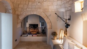 Une pièce chaleureuse avec un plafond en pierre, une cheminée, un canapé et une lampe.