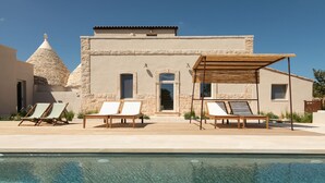 Un espace aménagé au bord de la piscine, avec des chaises longues et une pergola.