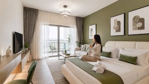 Een moderne hotelkamer met een bed, een bureau, een stoel, een balkon met uitzicht en kunstwerken aan de muren.