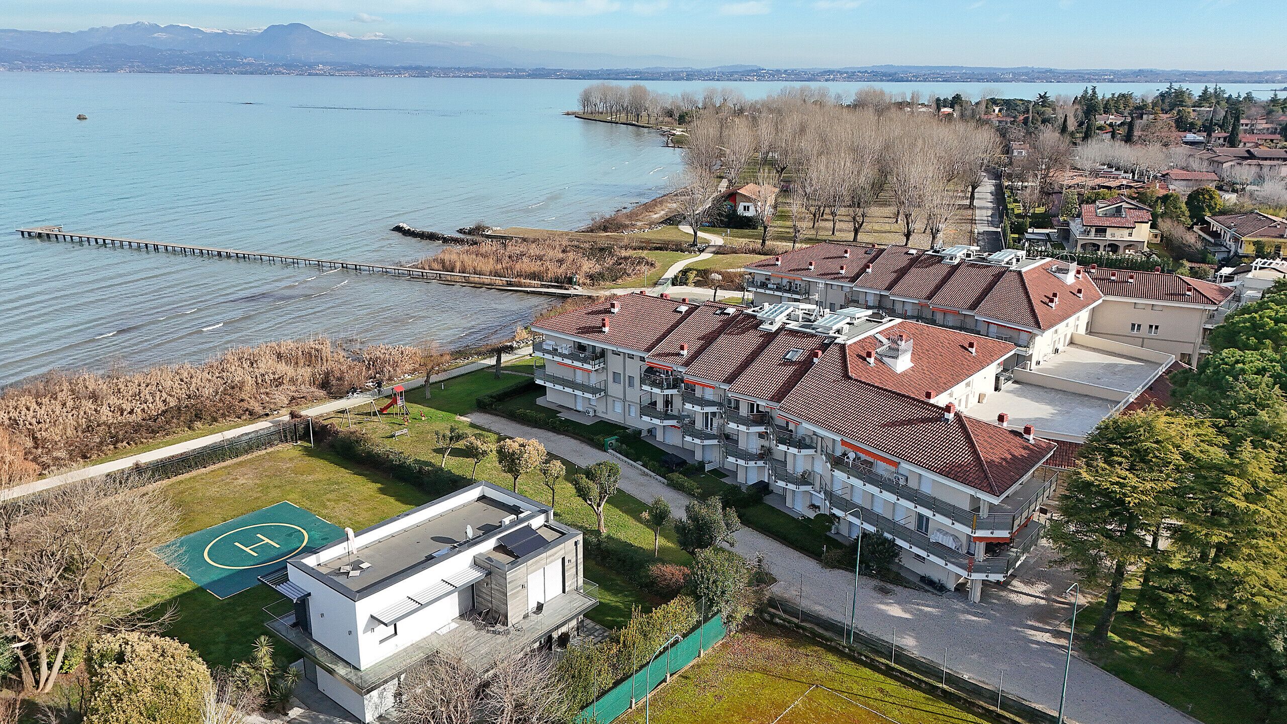 A residential area with a large building complex, a playground, and a view of a lake.
