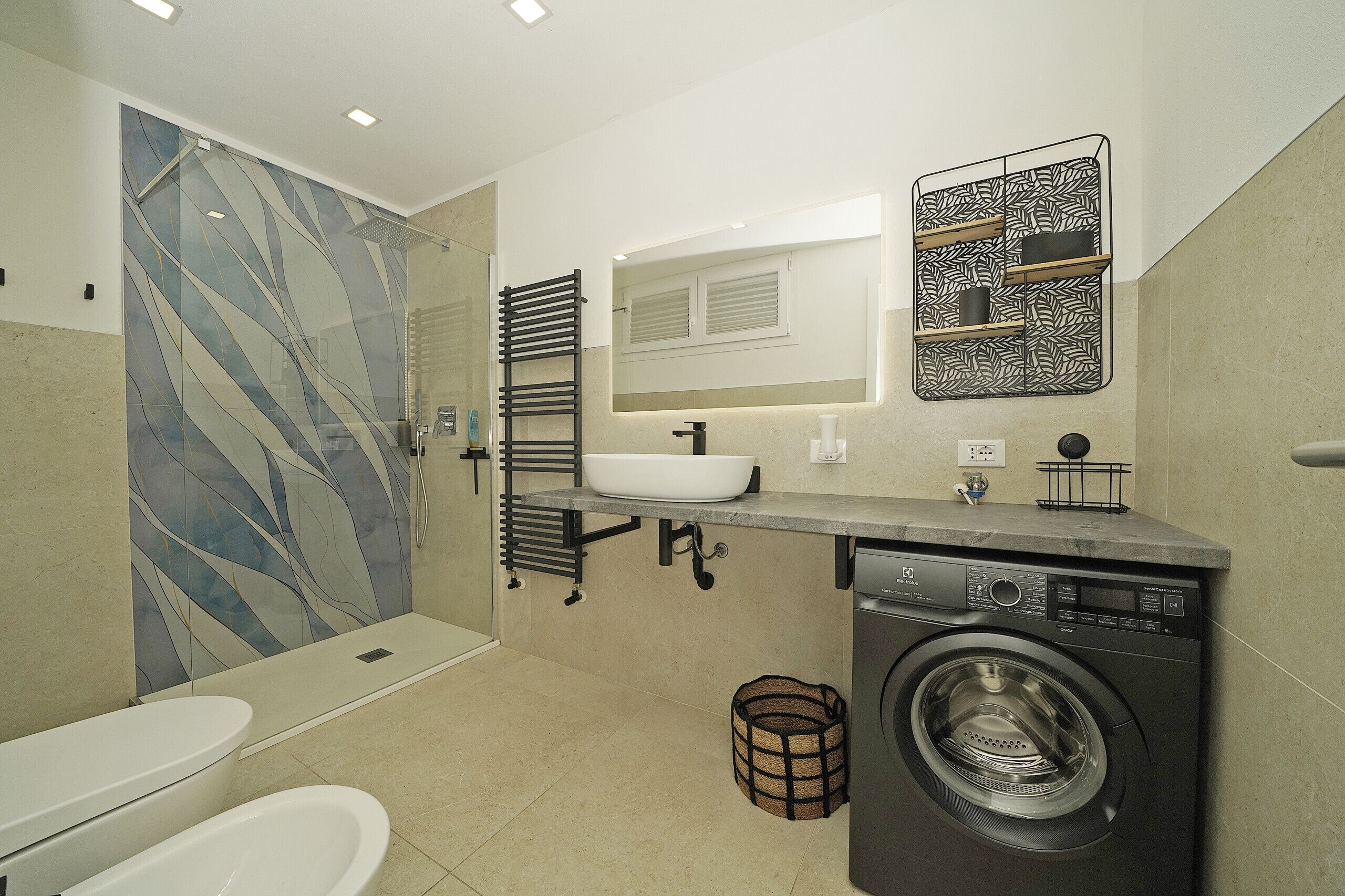 Un baño moderno con cabina de ducha de vidrio, lavabo integrado, lavadora e inodoro.