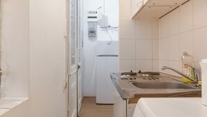 Eine schmale Küche mit Spüle, Herd und Kühlschrank.