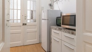 Eine kleine Küche mit weißen Schränken, einem Kühlschrank und einer Mikrowelle.