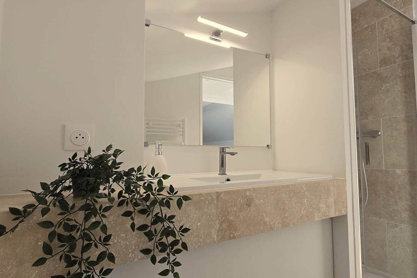 A bathroom with a sink, mirror, and shower.
