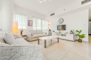 Ein modernes Wohnzimmer mit einer Couch, einem Couchtisch und einem an der Wand befestigten Fernseher.