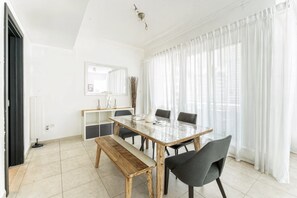 Ein moderner Essbereich mit einem Holztisch, schwarzen Stühlen, einer Bank und einem weißen Schrank.