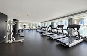 A gym with treadmills, weight machines, and a large window with a city view. - HAVN - 1 bedroom in Dubai Marina with Marina Views (Dubai)