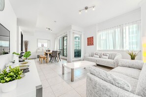 A modern living room with a sofa, coffee table, and dining area. - HAVN - 1 bedroom in Dubai Marina with Marina Views (Dubai)