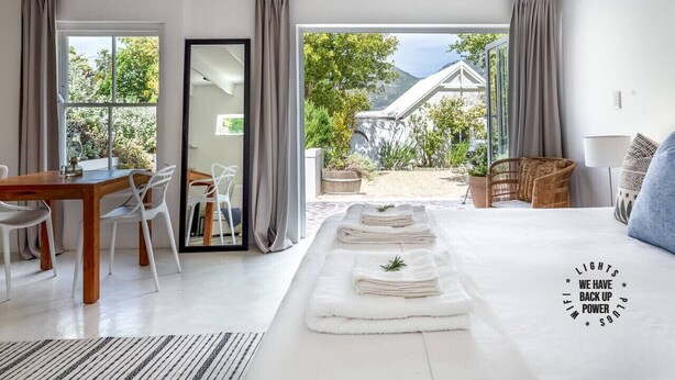 Een moderne slaapkamer met een groot bed, een zithoek en uitzicht op een tuin en bergen.