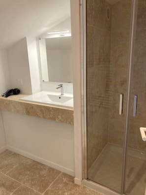 A bathroom with a glass shower enclosure, a sink with a mirror, and a towel rack.