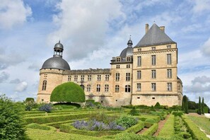 A large historic building with a prominent dome and a tower, surrounded by well-manicured gardens.