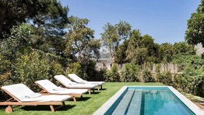 Ein Swimmingpool mit Liegestühlen und einem Holzzaun im Hintergrund.
