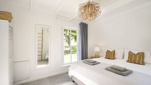 Ein Schlafzimmer mit einem großen Bett, einem Fenster mit Blick, einer Leiter und einer hängenden Leuchte.