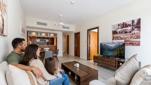 Un soggiorno moderno con divano, tavolino, televisore e opere d'arte alle pareti.