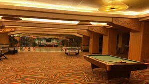 Un grand espace intérieur comprenant une table de billard, une autre table de billard et un comptoir d’accueil.