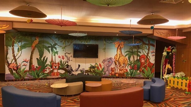 Un espace de jeux pour enfants agrémenté de peintures murales colorées, de sièges et d’un téléviseur.