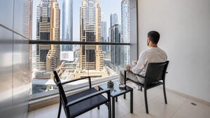 Um homem sentado perto de uma grande janela com vista para a cidade.